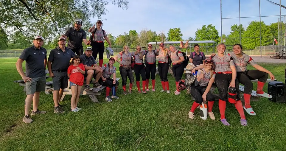 Players and coaches gathered around picnic tables after a game.